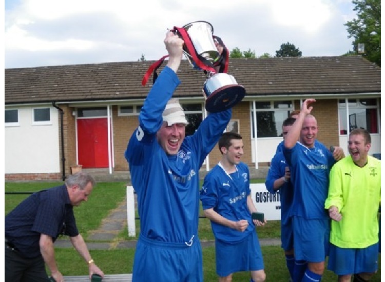 Skipper Paul Andison defies the pain to hold aloft the winners prize.
